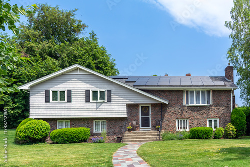 Elegant suburban family home with solar panels on the roof and landscaped front yard in Newton, Massachusetts, USA

