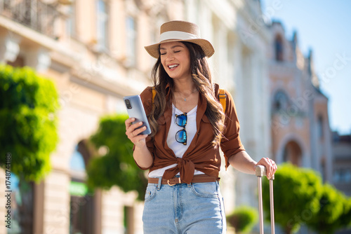 Happy woman traveling, checking phone in city street