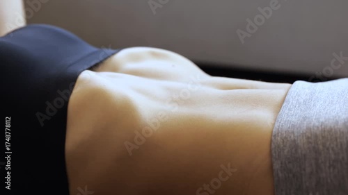 Young woman has workout at home during quarantine. Close up and side view of model training her abs muscles. Exercising hard. Strong sexy hot body.