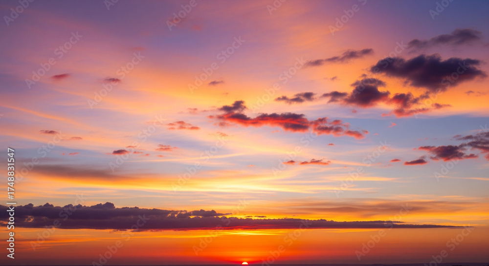 Fototapeta premium Vibrant sunset over the ocean with a colorful sky and scattered clouds at dusk