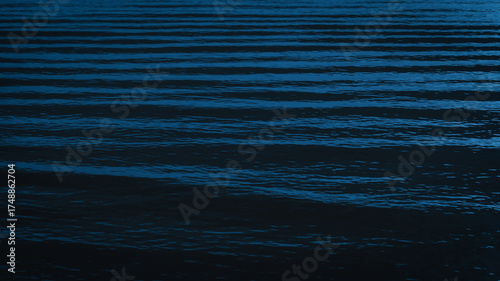 Dark and calm Prussian blue sea ripples forming elegant natural wave lines, perfect for abstract water background, texture, and graphic design project