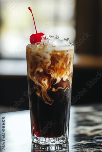 A tall glass of dirty soda sits on a table, featuring creamy swirls mixing into a dark cola base. The drink is topped with crushed ice and a bright red maraschino cherry,summer, refreshment, and sweet