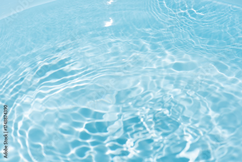 Blue water with ripples on the surface. Defocus blurred transparent blue colored clear calm water surface texture with splashes and bubbles. Water waves with shining pattern texture background.