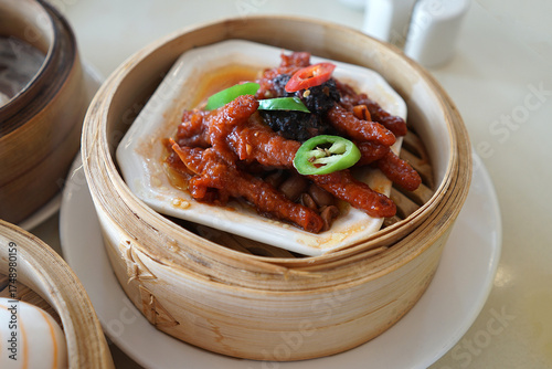Close up Braised Sichuan chicken feet served in wooden basket- Chinese Dim Sum