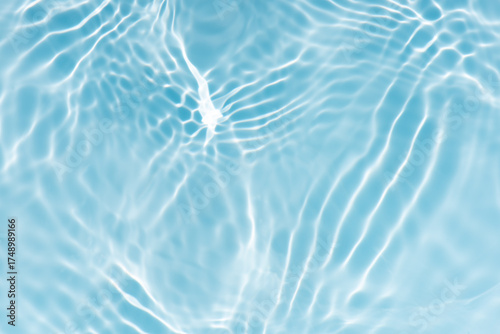 Blue water with ripples on the surface. Defocus blurred transparent blue colored clear calm water surface texture with splashes and bubbles. Water waves with shining pattern texture background.