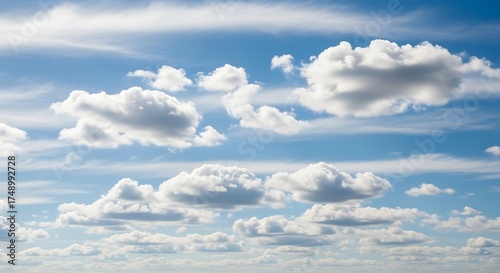 Clouds drifting in a bright blue sky on a sunny day.
