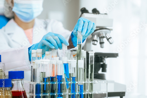 An Asian female scientist carefully analyzes microscopic samples and chemical solutions in a modern laboratory, conducting biology, microbiology, pharmaceutical, and medical research with precision