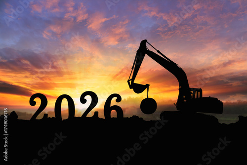 Concept happy new year 2026,crawler excavator silhouette with lift up bucket .On sunrise backgrounds