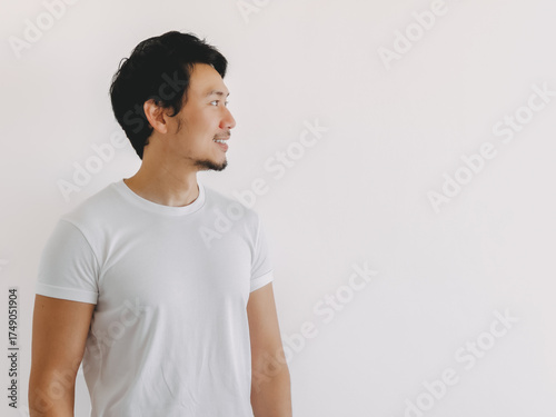 Asian man turning to the side with thoughtful gaze and neutral pose in white shirt and clean background