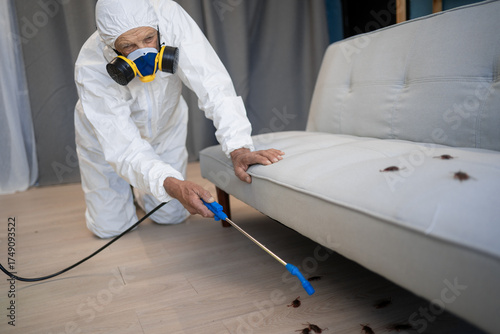Photos pest control worker wearing workwear spraying insecticide spray to cockroaches in the house while cleaning and insect eradication