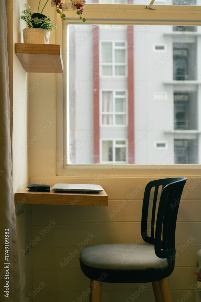 Obraz premium Cozy Workspace by the Window with Laptop and City View