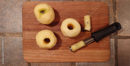 wooden cutting board with cored apples and apple corer