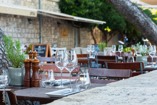 Eingedeckte Tiscche mit Besteck und Weingläsern auf der Terasse eines Restaurants auf der Stadtmauer der Altstadt von Korčula, Süddalmatien, Kroatien
