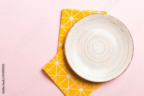 Top view on colored background empty round white plate on tablecloth for food. Empty dish on napkin with space for your design