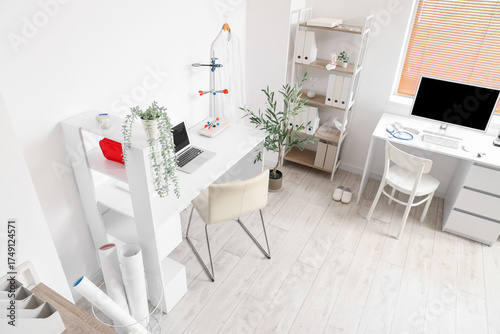 Modern home office with two desks, clean white interior, and various work setup