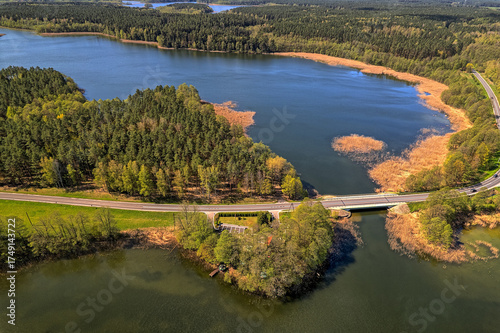Fototapeta Naklejka Na Ścianę i Meble -  Horizontal oblique aerial image of road bridge over lake with forested edges, Mazury Poland summer, drone, natural lighting, commercial stock