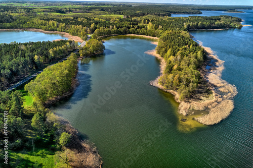 Fototapeta Naklejka Na Ścianę i Meble -  Aerial view of forested peninsula extending into Masurian lake, summer drone landscape