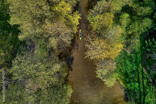 Fototapeta Naklejka Na Ścianę i Meble -  High-altitude shot of winding river cutting through green forest and fields in Mazury, Poland summer landscape