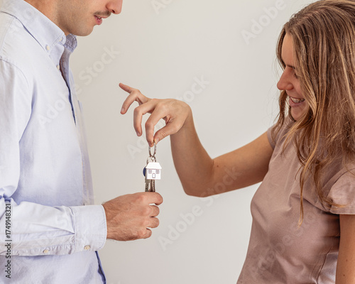 Young beautiful woman handling new apartment real estate keys to her partner