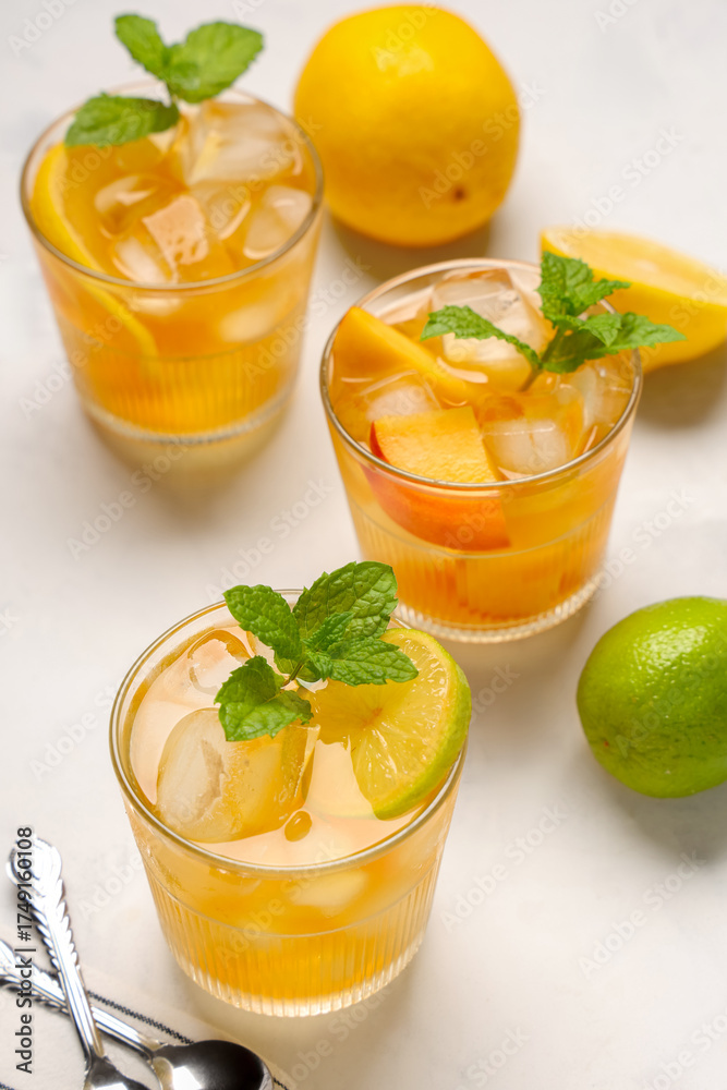 Fototapeta premium Refreshing summer drinks with ice, mint, and citrus slices on white background, healthy beverage