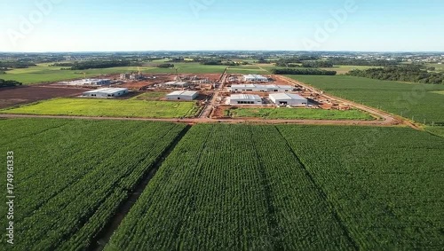 Wallpaper Mural Aerial view of a factory construction site surrounded by large, verdant agricultural fields under a clear, blue sky Torontodigital.ca