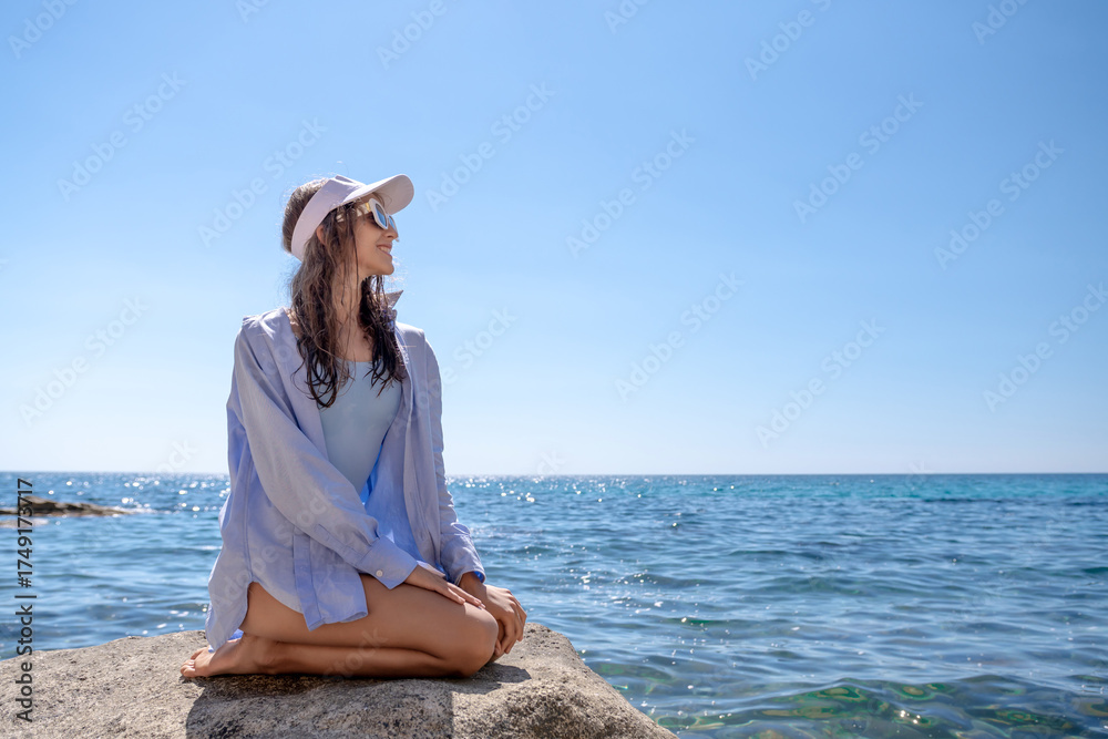 Φωτογραφία Woman Beach Relax: Young woman smiles on rock by blue ocean, enjoying sunny day after swimming