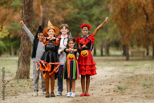 Group of kids dressed for Halloween with candies in park