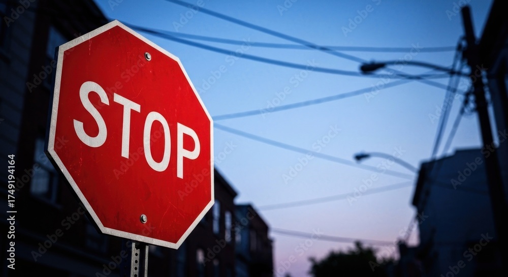Obraz premium Red stop sign with bold white letters against an urban twilight sky