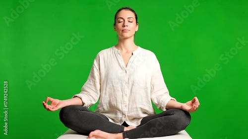 Young Woman Meditating in Lotus Position on Green Screen Background