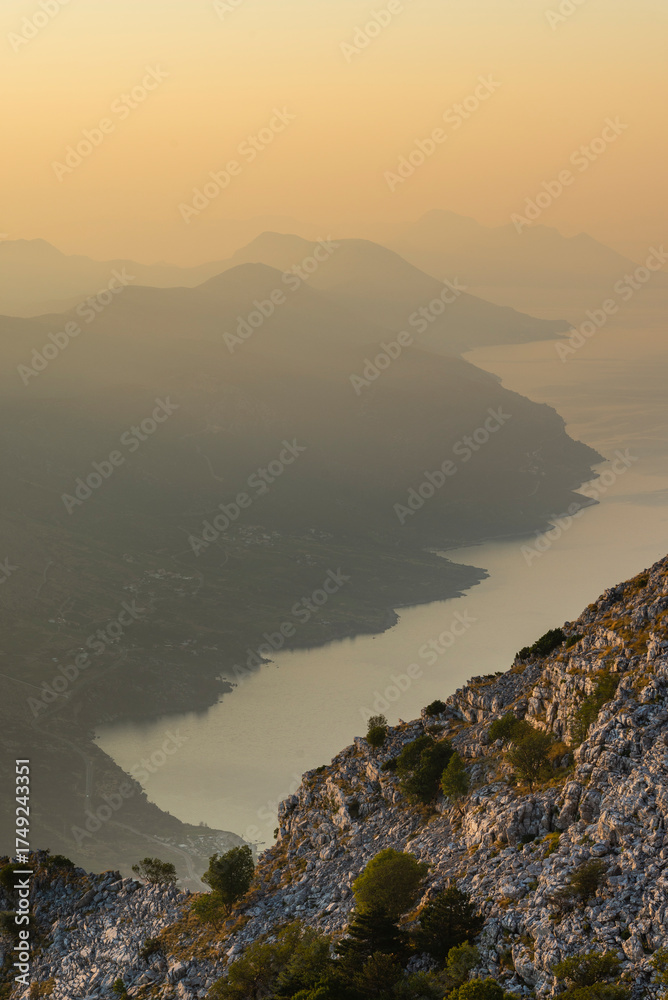 Fototapeta premium Die Bergketten an der Südküste der Halbinsel Pelješac verlieren sich im Dunst bei Sonnenaufgang, Süddalmatien, Kroatien