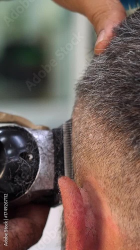 Vertical: A barber trims a client’s hair with an electric clipper, side angle showing meticulous technique, professional grooming, and contemporary style