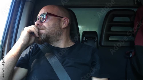 Middle aged man sits inside his car waiting to start, lost in thought, showing a calm and introspective moment before driving away.