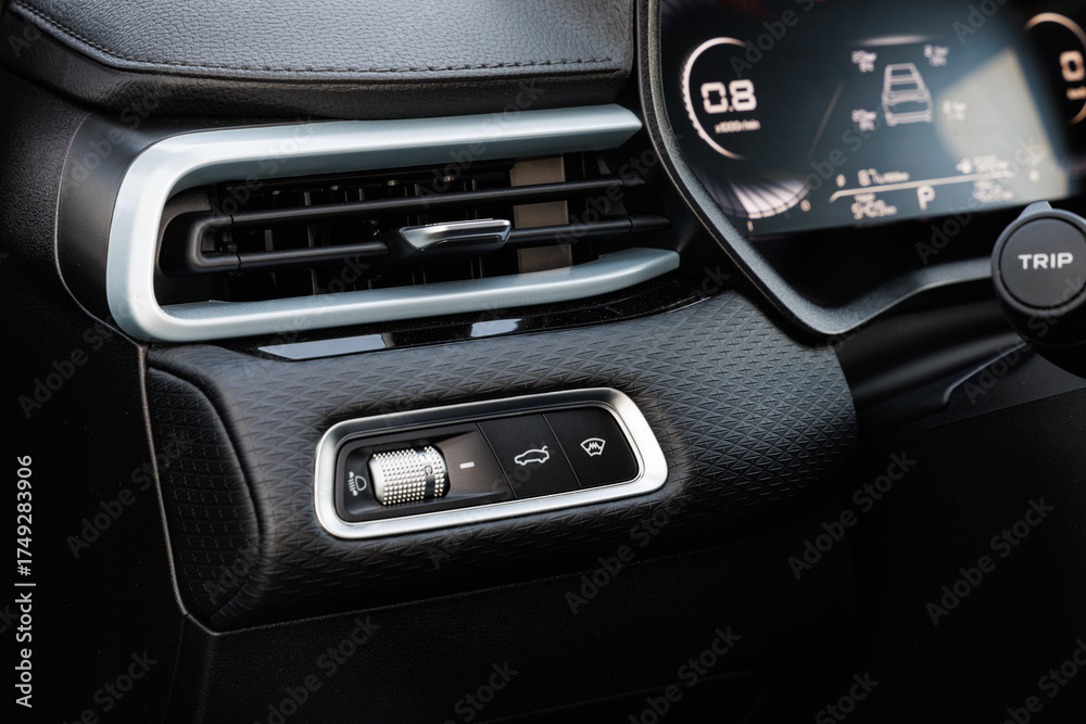 Fototapeta premium Close-up of car dashboard left of steering wheel, featuring headlight knob, TRIP button and digital cluster