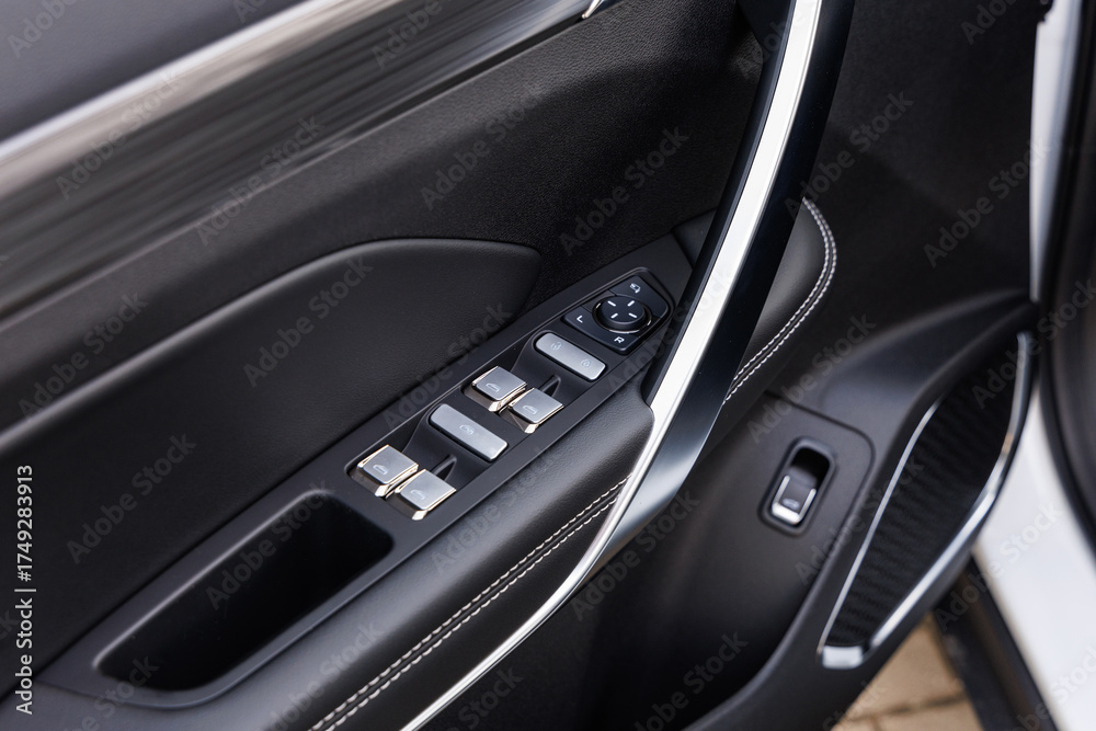Fototapeta premium Driver-side car door panel with power window switches, mirror adjustment pad and metallic handle