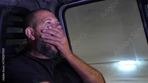 tired truck driver yawning repeatedly while driving through a tunnel at night, revealing exhaustion and the danger of fatigue behind the wheel.