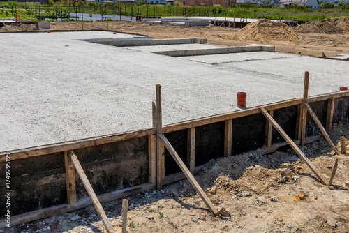 Workers pour cement to create a solid foundation slab for a new house in a residential development area under construction