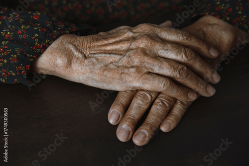 Close-up of wrinkled hands with visible veins resting on table