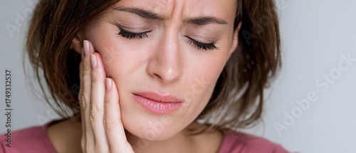 Stressed woman with hand on jaw suffering TMJ pain from nighttime grinding

