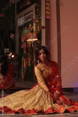 Portrait of an Indian Nepali woman wearing traditional red and golden lehenga sitting gracefully indoors with festive lights in background