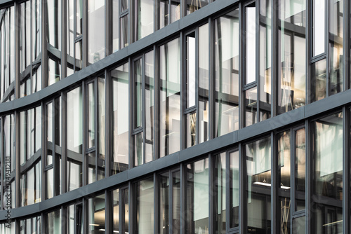 Wallpaper Mural Complex glass and steel facade with overlapping layers, visible offices, and reflections of interior lighting creating depth in modern architecture Torontodigital.ca