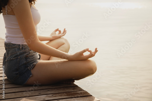 Female hands in a meditation gesture on a pier facing the sea
