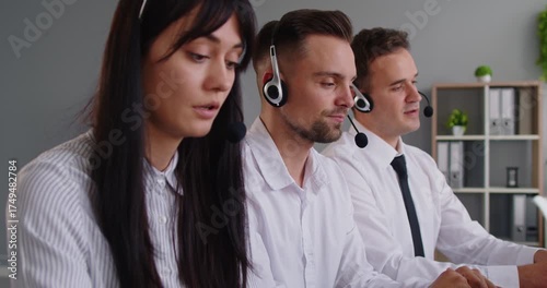 Operators with headsets handle support in a callcenter typing on laptops in an office to provide service, helpdesk solutions, and teamwork for customers. Three agents focus on important tasks.