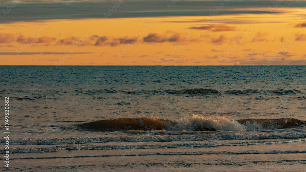 Obraz premium The coast of the Arctic Ocean. Summer in the Arctic Circle. Night. Beautiful cloudy sky in the light of the setting sun. Calm ocean surface
