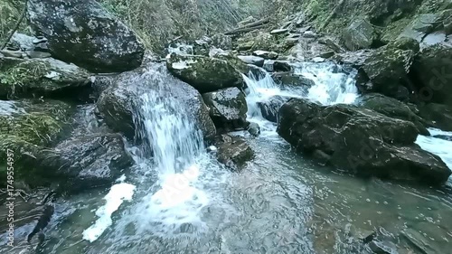 A small beautiful stream with stones in the bed, flows through the morning autumn forest illuminated by the rays of the rising sun. The Tevenek River, Altai, Siberia, Russia.