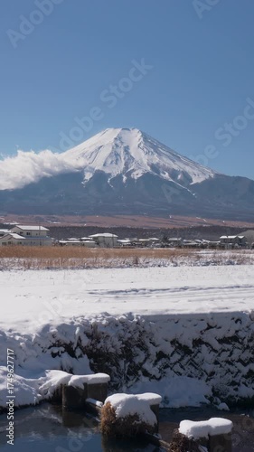 山梨県忍野村より除く雪に覆われた田園風景越しの富士山のタイムラプス映像（縦・フィックス）
