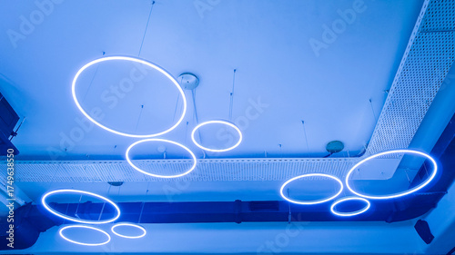 Circular luminaires on white ceiling. Circular LED luminaires on suspended ceiling, modern lighting system for office space, co-working spaces, conference rooms, educational institutions. Real photo
