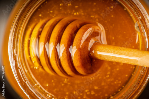 Fotografie Honey dipper submerged in golden honey