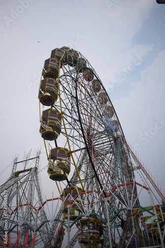 Closeup of multi-coloured Giant Wheel during Dussehra Mela in Delhi, India. Bottom view of Giant Wheel swing. Ferris wheel with colourful cabins during evening time.