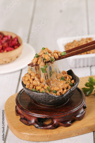 Traditional Japanese Natto Fermented Soybeans in Black Bowl with Chopsticks on Wooden Board