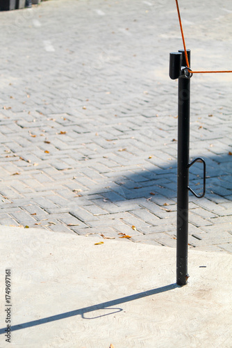 Black metal pole casting shadow on pavement